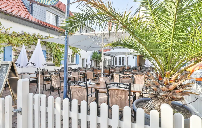 Biergarten mit Palmen und weißen Sonnenschirmen