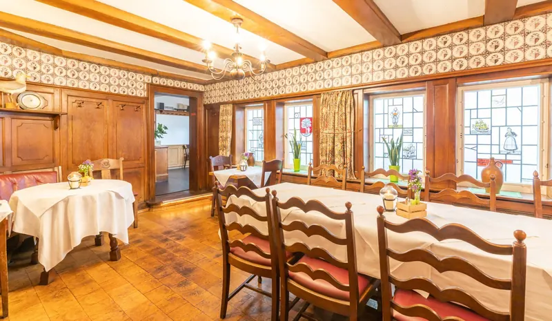 Stube mit Holzvertäfelung, Delfter Kacheln und langer Tafel